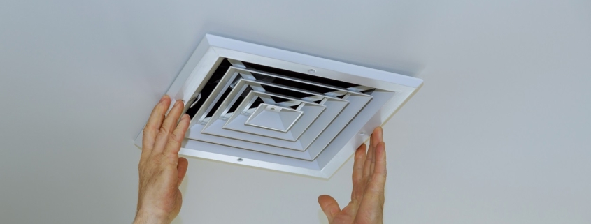 Close up man hand installing vent cover from ceiling Mounted Air Conditioner.