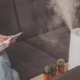 Household humidifier at home on table near woman reading on sofa